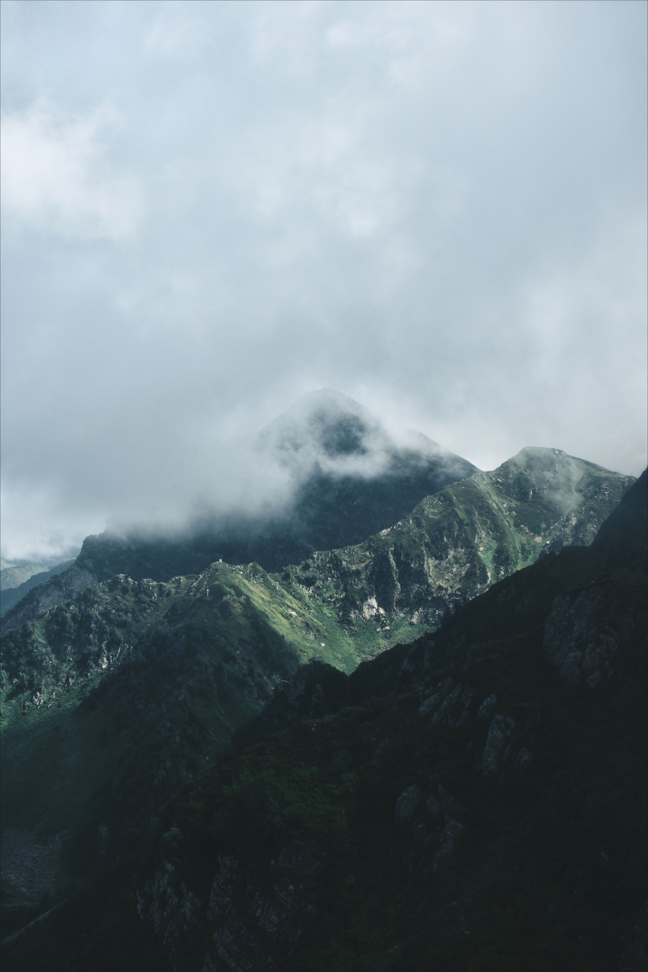 Green mountain ridge with low cloud drifting across the summit